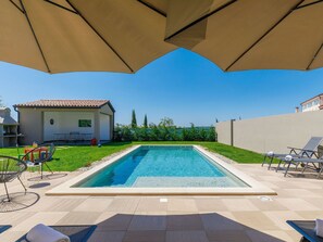 Relax by the pool surrounded by a clean deck and shaded seating area.