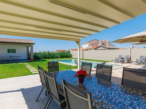 Relax in a serene outdoor space with a pool view, comfortable seating, and lush greenery.