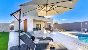 A modern outdoor patio with a pool, lounge chairs, and a large umbrella. - Stunning private villa with A/C, private pool, WIFI, hot tub, TV, terrace and pets allowed (Novi Vinodolski)