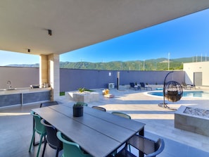 A rooftop patio with a pool, outdoor seating, and a view of the mountains.