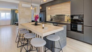 A modern kitchen with a central island, bar stools, pendant lighting, and a large window with curtains. - Stunning private villa with A/C, private pool, WIFI, hot tub, TV, terrace and pets allowed (Novi Vinodolski)