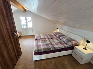 A bedroom with a bed, nightstands, a window, and a wooden ceiling.