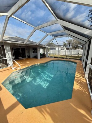 A covered swimming pool with a clear blue water surface, surrounded by a white structure with a roof.