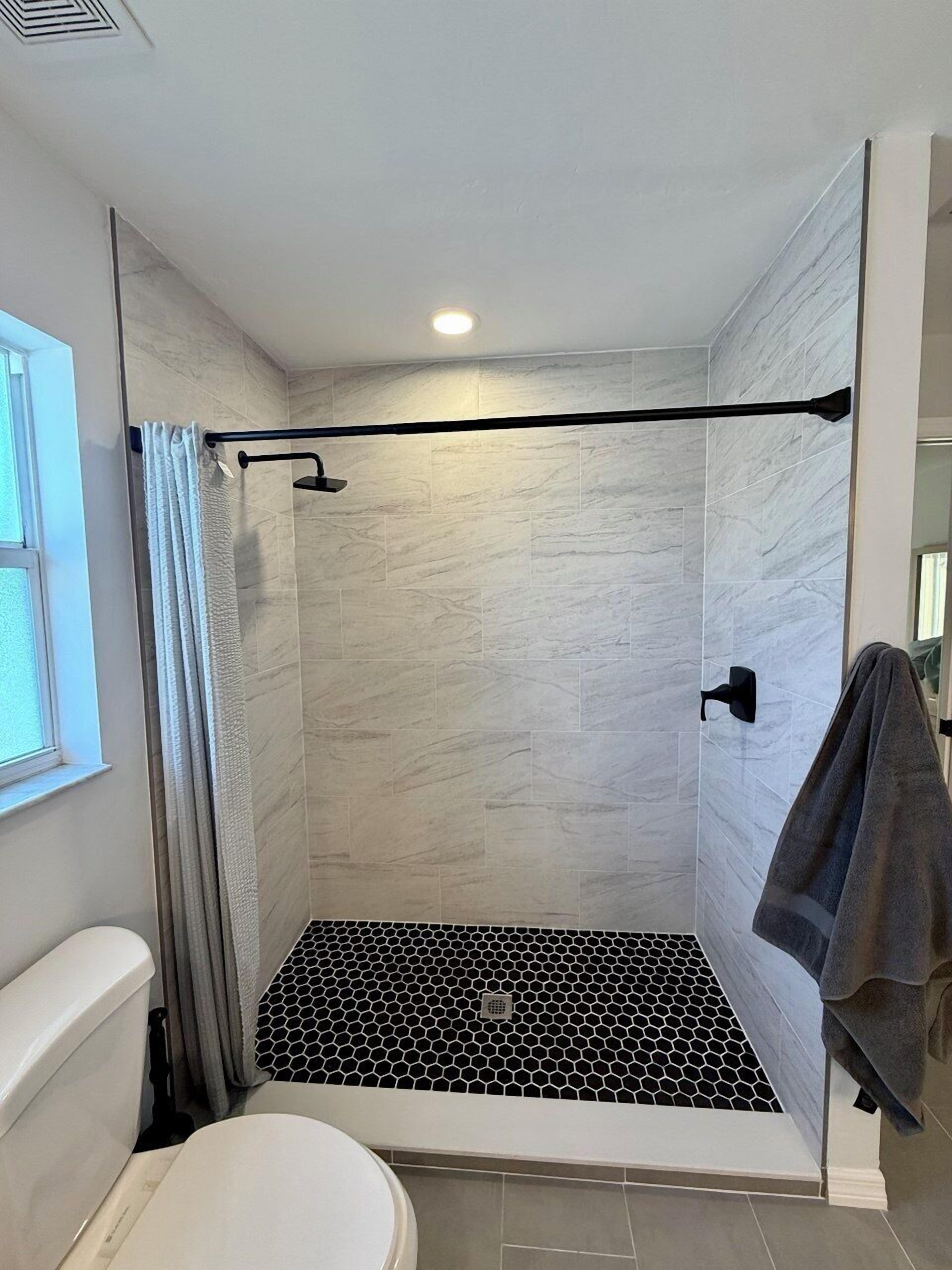 Une salle de bain moderne comprenant un espace douche, des toilettes et un porte-serviettes.
