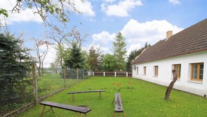 Une cour verdoyante avec des tables de pique-nique et un bâtiment blanc doté de fenêtres.