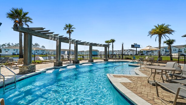 A swimming pool with lounge chairs and palm trees.