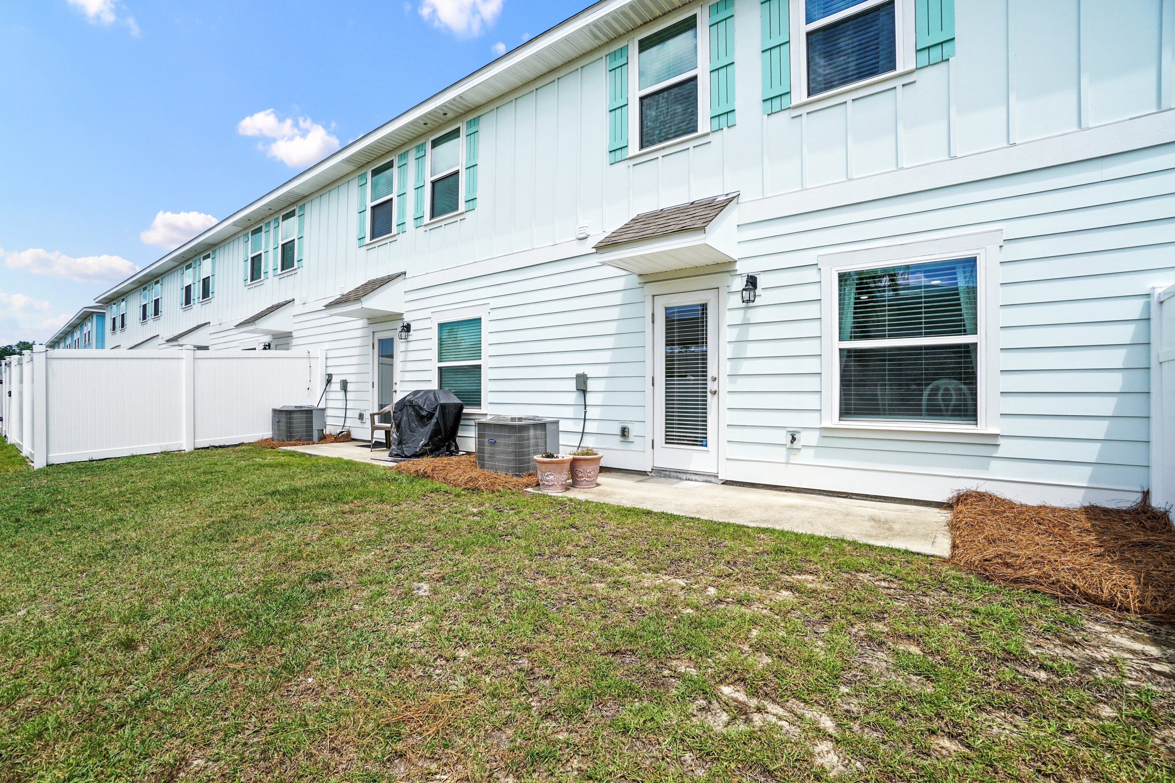 A two-story house with a covered patio area, a small outdoor grill, and a well-maintained lawn.