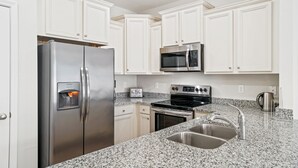A kitchen with white cabinets, stainless steel appliances, granite countertops, and a stainless steel sink.