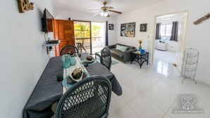 Un amplio espacio de sala con una mesa de comedor, sillas, un sofá y un ventilador de techo.