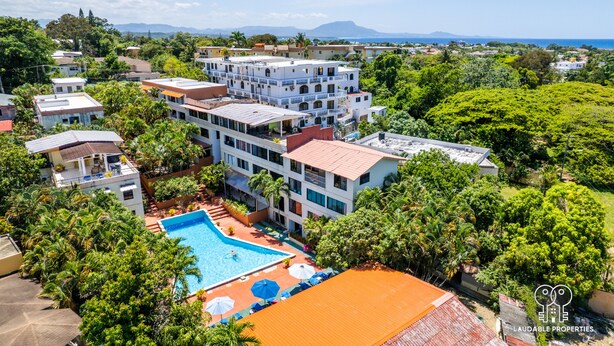 Un resort con piscina rodeada de exuberante vegetación y varios edificios.