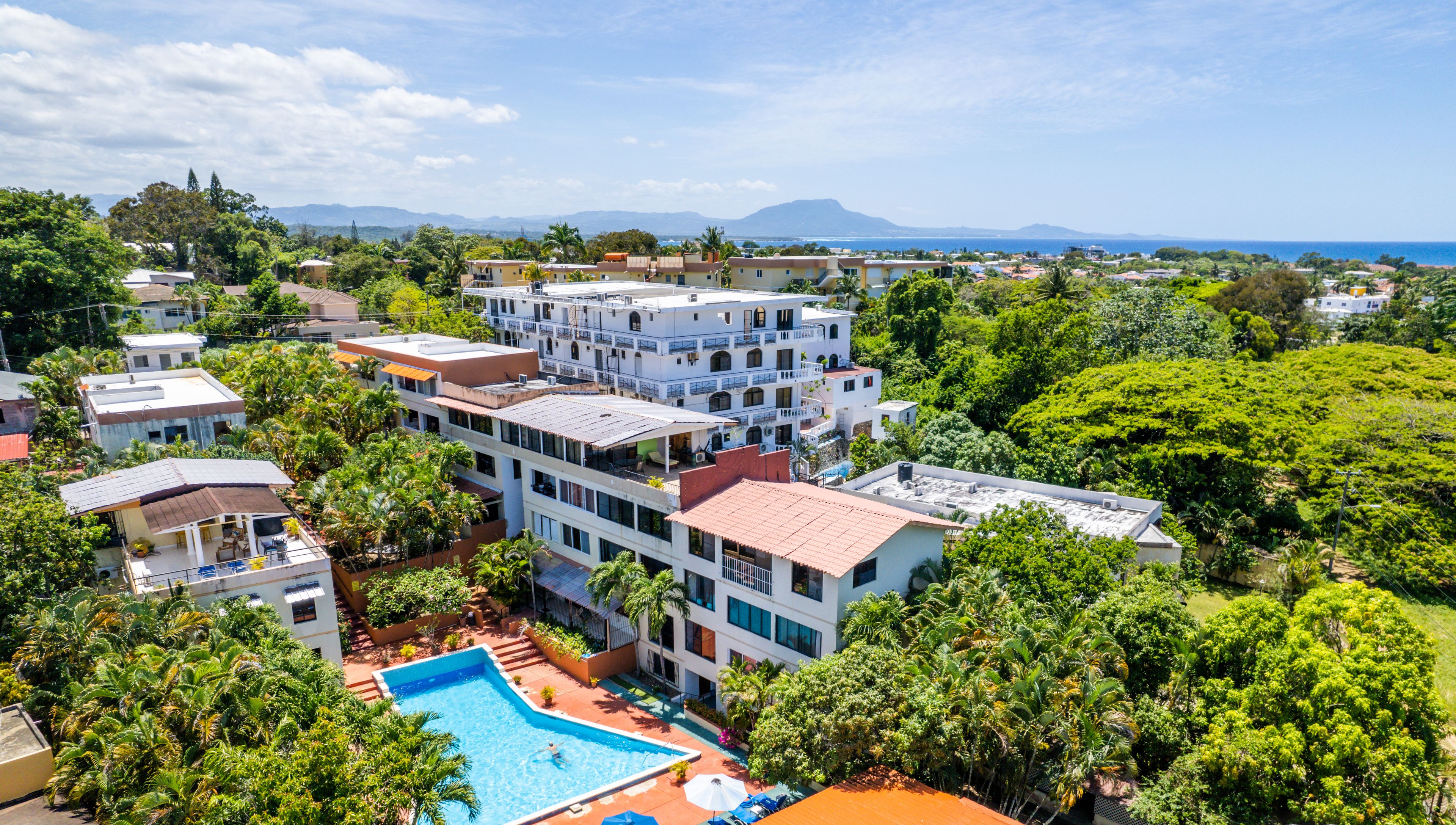 Un resort con piscina rodeada de exuberante vegetación y varios edificios.
