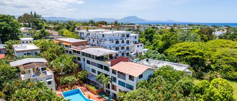 Un resort con piscina rodeada de exuberante vegetación y varios edificios.
