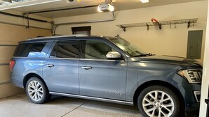A gray SUV parked in a garage with a concrete floor and a metal door in the background. - Luxury 3 Bedroom Mountain Townhome in Keystone (Dillon)