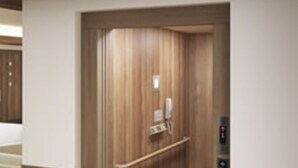 An elevator with wooden paneling and a handrail, leading to a landing with a phone and a wall-mounted control panel. - Asakusa HomeSuites Tokyo (Tokyo)
