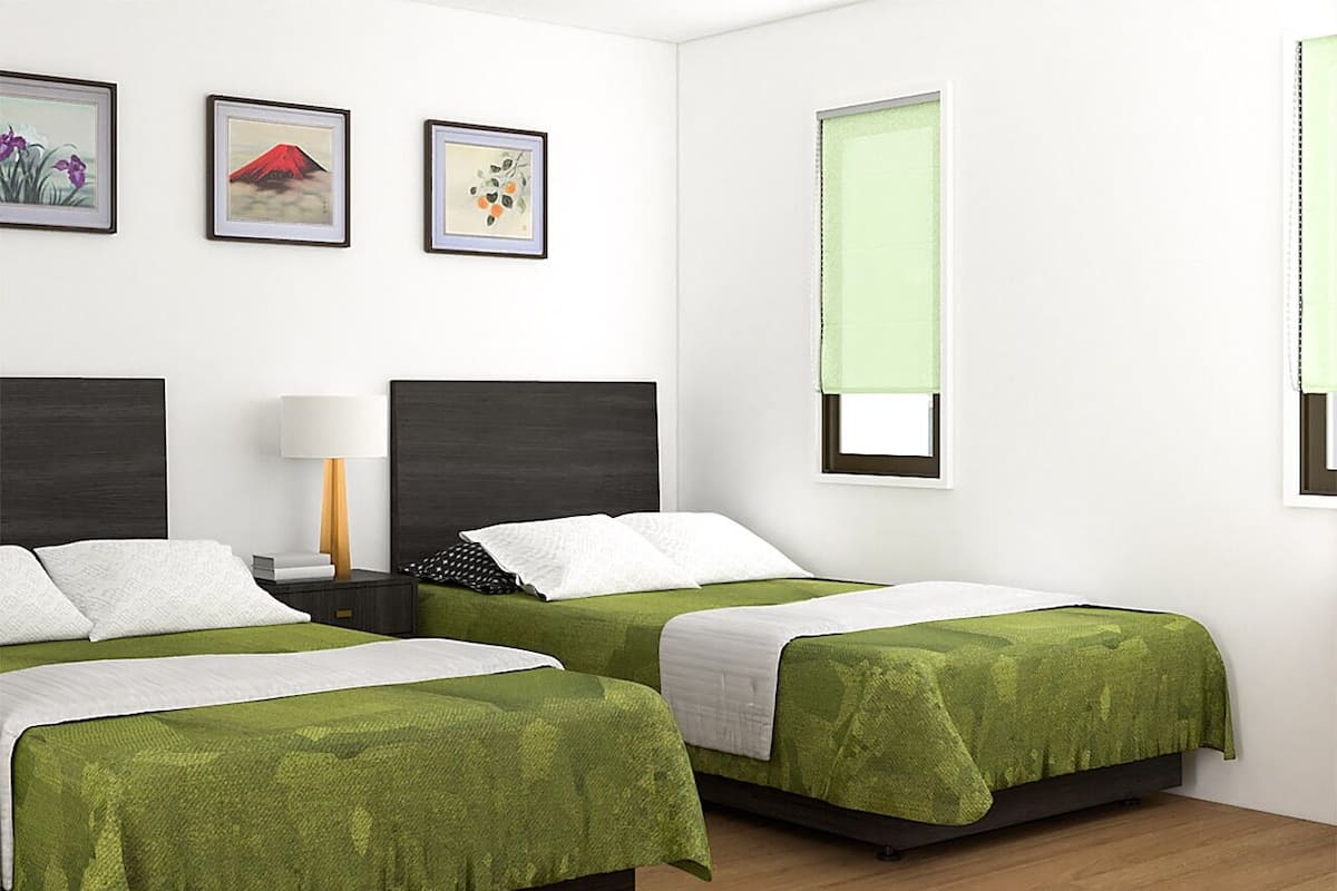 Habitación de hotel con dos camas, una mesita de noche, una lámpara y tres cuadros en la pared.