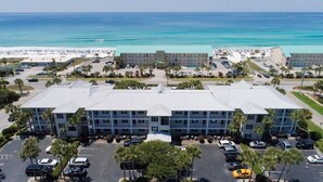 Ein mehrstöckiges Hotel mit flachem Dach, Parkplatz und Blick auf den Strand.