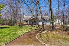 A two-story house with a front porch, surrounded by trees and a well-maintained lawn.