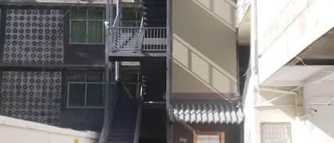 A multi-story building with a fire escape, a garage door, and a visible entrance.