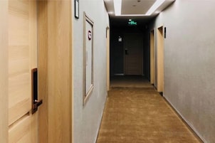 Pasillo de hotel con puertas de madera, suelo alfombrado y un cartel con un número de habitación.