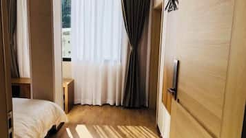 Una habitación de hotel con una cama, una puerta de madera y una ventana con cortinas.