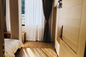 Una habitación de hotel con una cama, una puerta de madera y una ventana con cortinas.