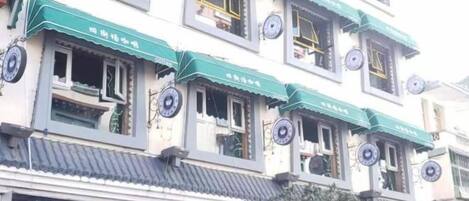 Een hotel met traditionele Chinese architectuur, herkenbaar aan groene luifels en ronde decoraties op de ramen.