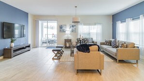 A modern living room with a sofa, TV, and entertainment unit. - Luxury 5 Bedroom 4 bath private pool Home 117 (Reunion)