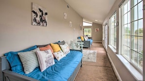 Ein Korridor mit einem blauen Sofa, einem kleinen Tisch und Stühlen, der zu einem Raum mit einem großen Fenster führt.