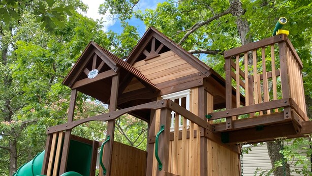 A wooden playhouse with a slide, a small staircase, and a lookout tower. - Niangua Hills Resort (Camdenton)