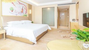 A hotel room with a bed, bedside table, a TV, a small table with a plant, and a painting on the wall. - Vienna International Hotel (Jinan Shandong International Convention and Exhibition Center) (Jinan)