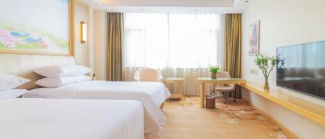 A hotel room with two beds, a desk, a chair, a TV, and a window with curtains.