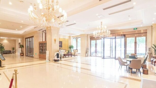 A spacious lobby with a marble floor, a reception desk, a chandelier, and a seating area with tables and chairs. - Vienna International Hotel (Jinan Shandong International Convention and Exhibition Center) (Jinan)