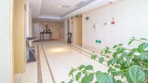 A hotel corridor with a marble floor, wooden doors, and a plant in the foreground. - Vienna International Hotel (Jinan Shandong International Convention and Exhibition Center) (Jinan)