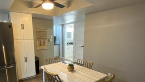 Une cuisine moderne avec des meubles blancs, un réfrigérateur en acier inoxydable et une table à manger avec des chaises.
