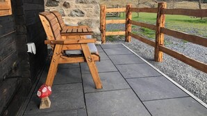 Un banco de madera con cojín, un muro de piedra y una valla de madera en una zona montañosa.