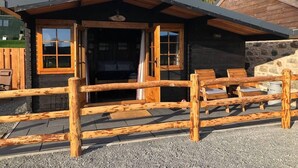 Un refugio rústico con fachada de madera, un muro de piedra y un camino de entrada de grava.