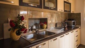 A modern kitchen with stainless steel appliances, a vase with red roses, and a dish rack.
