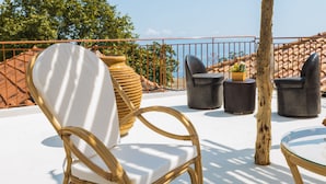 A terrace with wicker chairs, a glass table, and a potted plant.