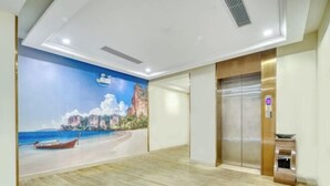 Eine Hotellobby mit Wandgemälde einer Strandansicht, einem Aufzug und einer Rezeption.