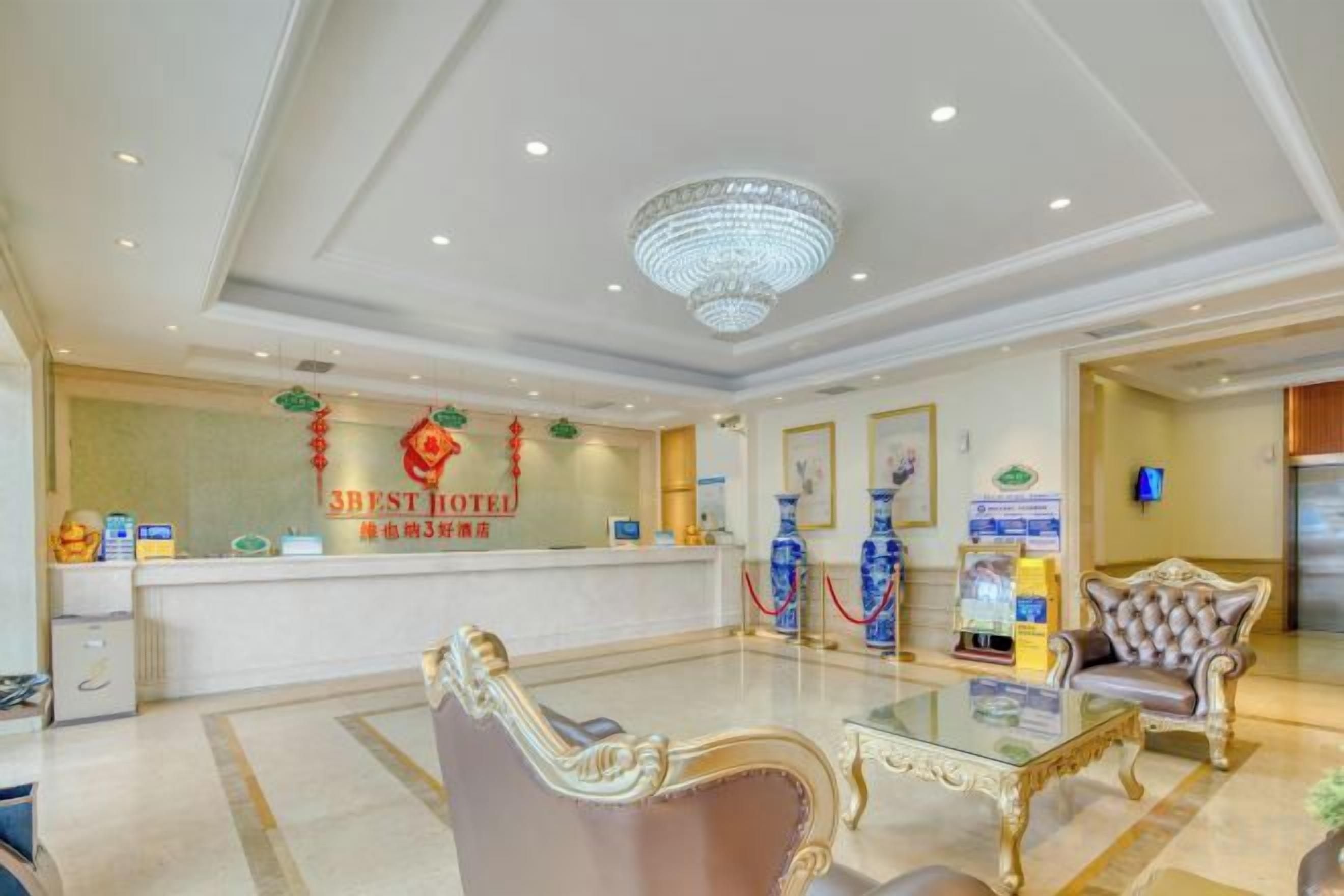 A hotel reception area with a reception desk, seating area, and a chandelier.