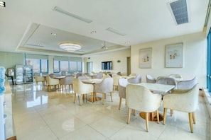 A spacious dining area with multiple tables and chairs, large windows, and a modern chandelier. - Vienna 3 Best Hotel (Foshan Jinsha Central Square) (Foshan)