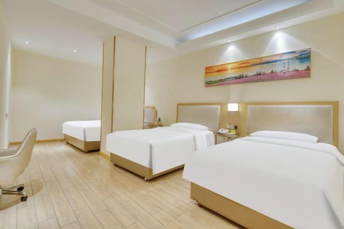 A hotel room with three beds, a desk, and a chair.
