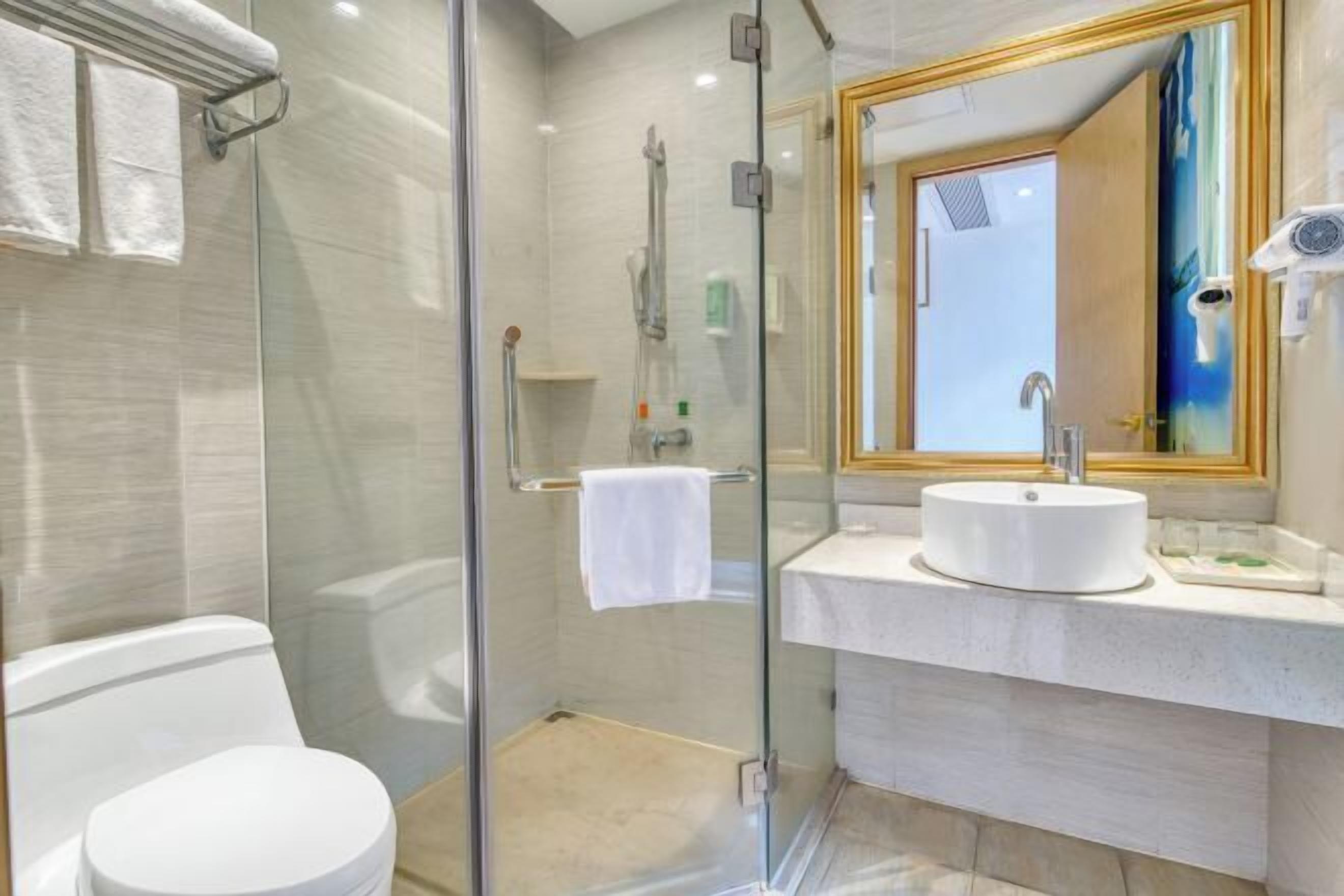 A modern bathroom with a glass-enclosed shower, a white toilet, and a vanity with a large mirror.
