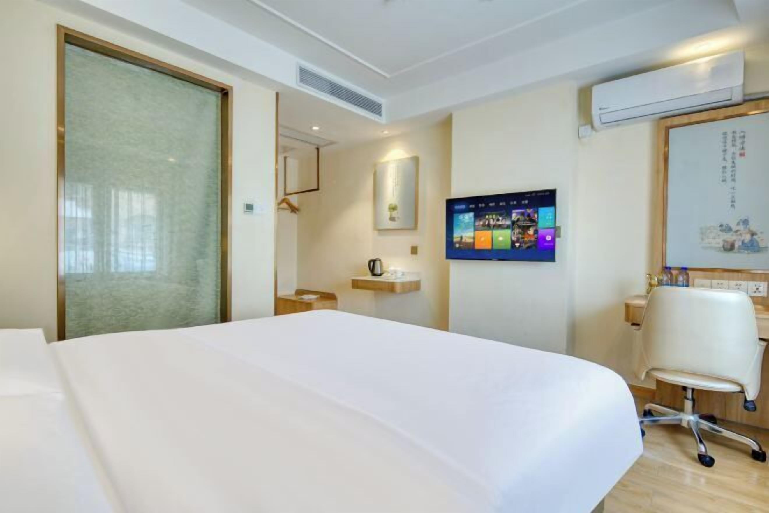 Habitación de hotel con cama, escritorio, silla, televisor y aire acondicionado instalado en la pared.