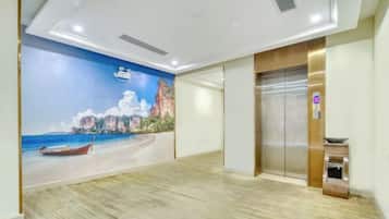 A hotel lobby with a mural of a beach scene, an elevator, and a reception desk.