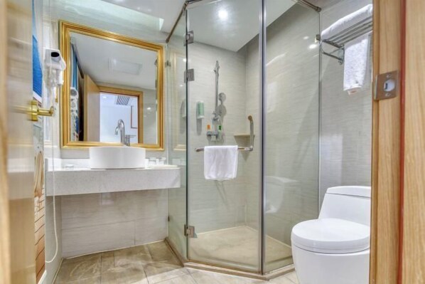 A modern bathroom with a glass-enclosed shower, a white toilet, and a vanity with a gold-framed mirror. - Vienna 3 Best Hotel (Foshan Jinsha Central Square) (Foshan)