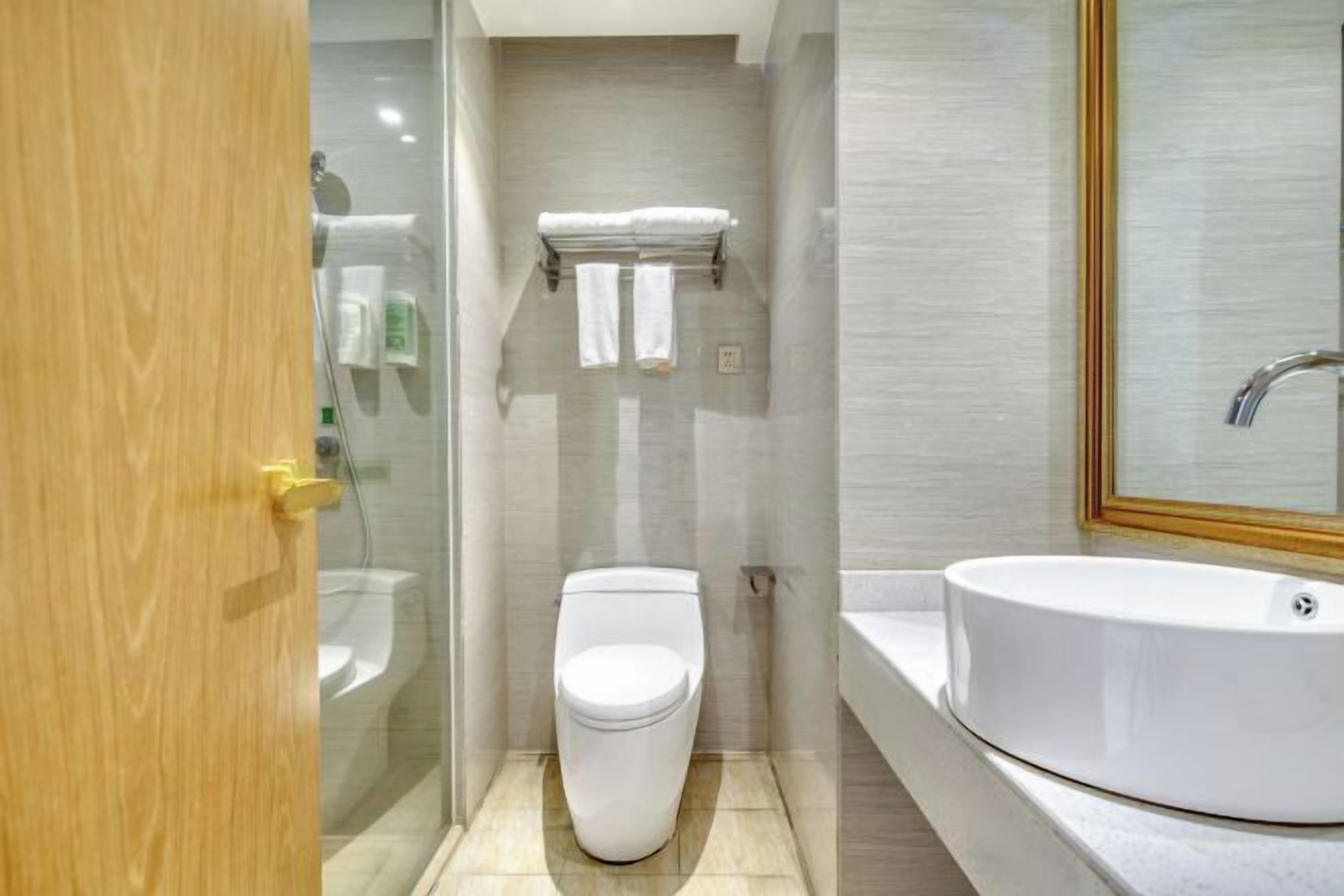 Un baño moderno con inodoro, lavamanos y cabina de ducha de vidrio.