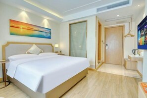 A hotel room with a large bed, a painting on the wall, a desk with a kettle, and a door leading to another room. - Vienna 3 Best Hotel (Foshan Jinsha Central Square) (Foshan)