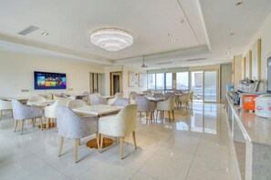 A spacious dining area with multiple tables and chairs, a television screen, and a large chandelier. - Vienna 3 Best Hotel (Foshan Jinsha Central Square) (Foshan)