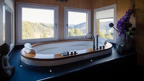 Une salle de bain moderne avec une baignoire sur pieds, de grandes fenêtres et une statue de Bouddha.